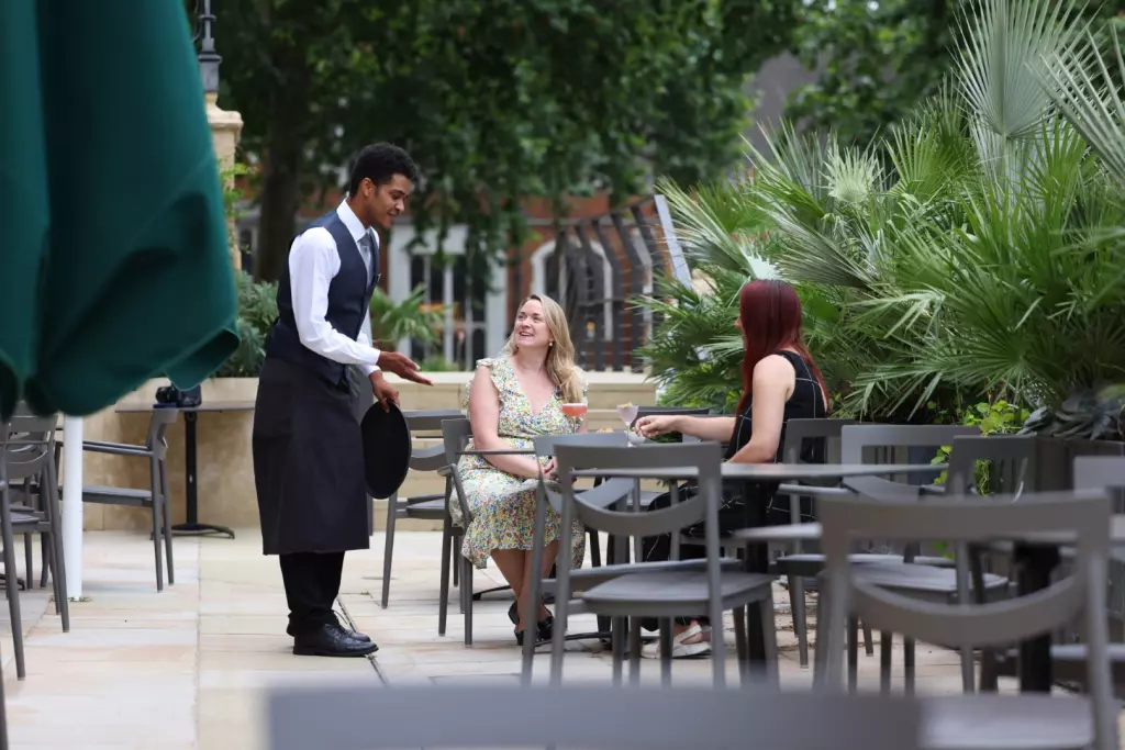 Staff attending to two women sat at outdoor terrace